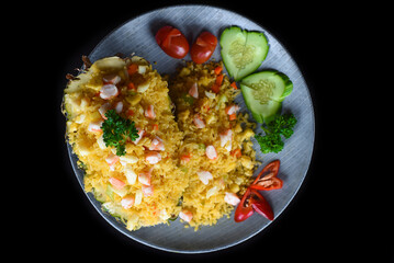 Fried rice with seafood in a pineapple with vegetables on blue plate isolated on black background top view  