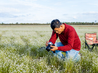 Naklejka na ściany i meble photographer taking pictures of flowers in the beautiful meadow.