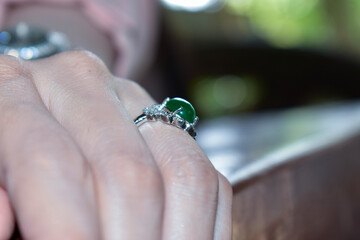 The Jade Ring is a white gold ring decorated with green jade on the finger.