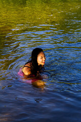 Young Japanese American Woman Sitting In River In Dress