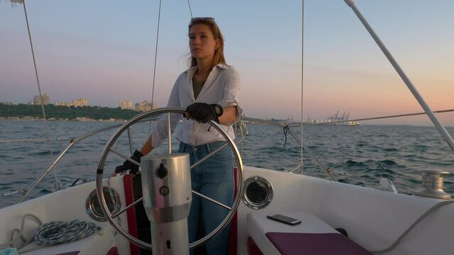 woman captain steering a yacht at sunset, luxury voyage at sea, man holding a steering wheel of a sailboat, summer vacation, travel concept