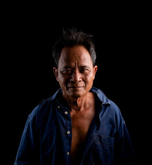 Portrait of an elderly Asian man wearing a blue shirt on a black background.