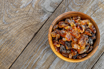top view of brown lump caramelized sugar in bowl on wooden table