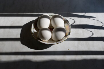 Chicken eggs in a plate on the kitchen table.