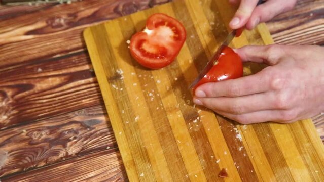 Man hands slicing a tomato for a salad, pizza, burger. Top view. Homemade healthy dinner meal concept