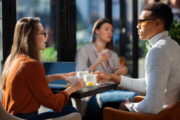 Three friends in a restaurant talking smiling and drinking tea. Business colleagues having a meeting after work or during coffee break at a cafe bar.