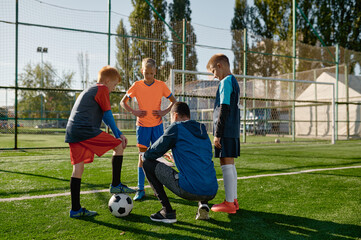 Soccer coach reviewing strategies with young boys soccer players