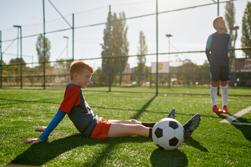 Young boy soccer player rest on field during break in training