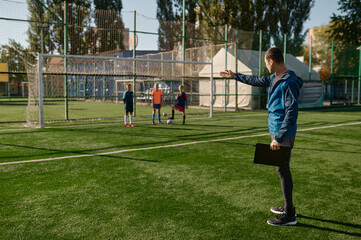 Coach giving instructions to children football team players during training