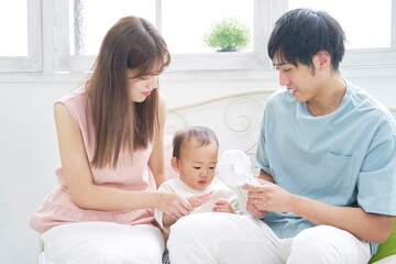 Obraz premium 赤ちゃんにハンディファンを使う父親