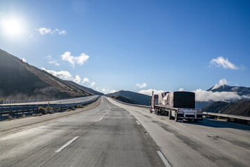 Heavy duty classic red big rig semi truck transporting covered cargo on flat bed semi trailer...