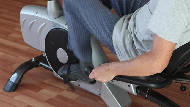 On an exercise bike, man pedals, close-up of legs.