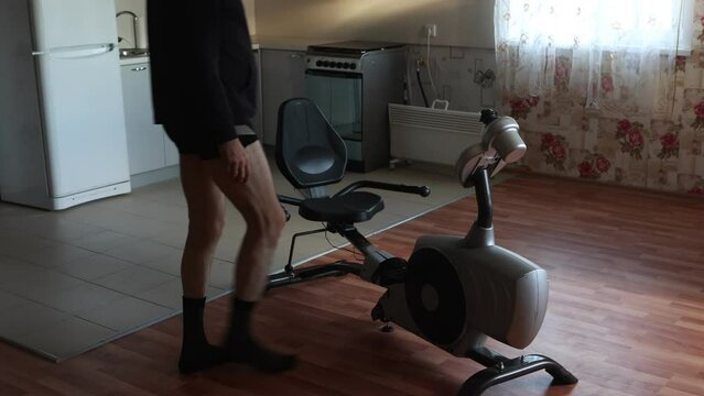 Flabby man on an exercise bike, an unsportsmanlike elderly male pedaling.