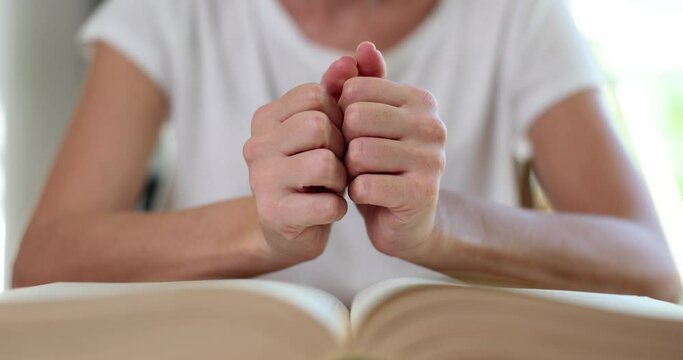 Woman prays with hands clasped on Bible faith and hope