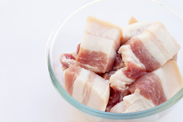 Streaky pork in glass bowl on white background.