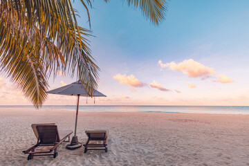 Beautiful panoramic paradise tropical beach sunset as summer island landscape with beds umbrella palm leaves calm sea shore coast. Luxury travel panorama couple destination banner for vacation holiday