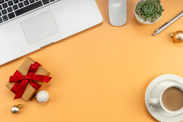 Christmas office table with coffee cup, laptop, Xmas decorations on yellow background. Flat lay, top view. New Year workspace.