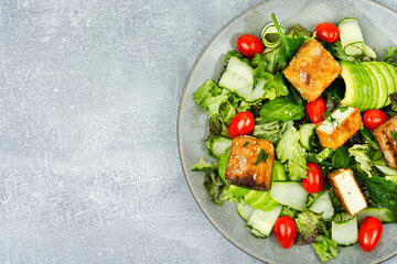 Healthy salad of grilled tofu cheese and fresh vegetables.