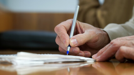 The hand of an adult man with a fountain pen, writing in a notebook. No face. Selective focus