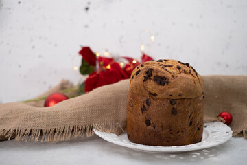 Warm atmosphere with chocolate chips panettone and red flowers and bokeh effect