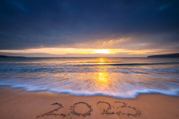 Happy New Year 2023 travel, sport, meditation concept, text lettering on the ocean beach sand at...