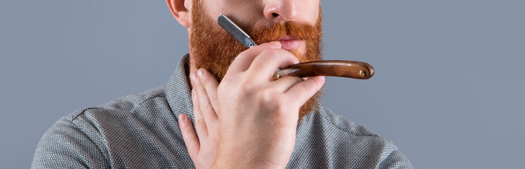 cropped view of man in barber studio. man hold barber blade for shaving. man shaving with blade
