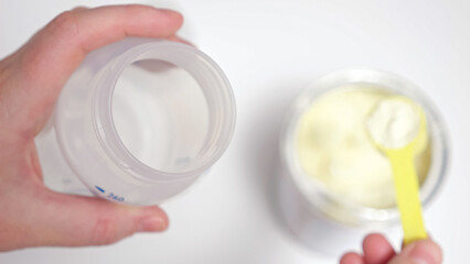 Parent takes powder with scoop to make milk mixture for baby at home. Person takes care of kid health and wants to make child satisfied with food fusion