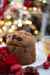 Chocolate chips Panettone and cups of tea in white table with red festive balls and bokeh background. High quality photo