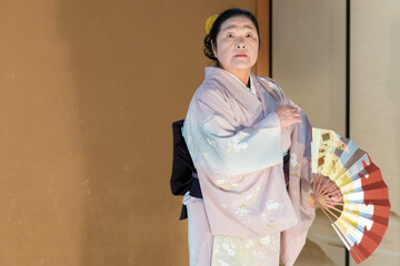 着物姿で扇子を持って日本舞踊を踊る年配の日本人女性