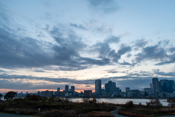 Riverside dawn view with a blue sky, some plants, and some buildings in the background
