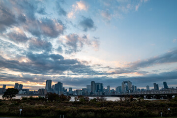 View of a park with buildings and a bridge in the background during sunrise