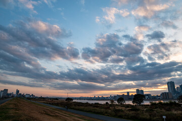 View of a park with buildings and a river in the background during sunrise