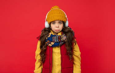 modern life in childhood. unhappy child listen music in headphones. kid wear warm clothes.