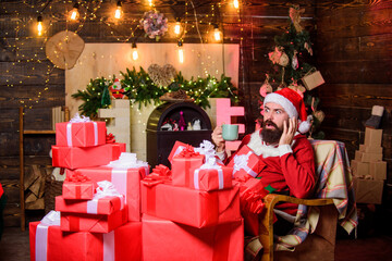 Greetings from Santa. Bearded man sit in armchair with pile of gifts. Parcels gifts will be delivered to its destination. Sending gifts. Santa claus residence. Winter holidays. Cozy home atmosphere