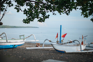 Aerial view of Amed beach in Bali, Indonesia. Traditional fishing boats called jukung on the black sand beach and Mount Agung volcano