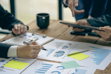Group of Asian businessmen meeting Looking at graphs, indexes and figures on computer laptop screen with financial report discussing business plan for investing analysis concept