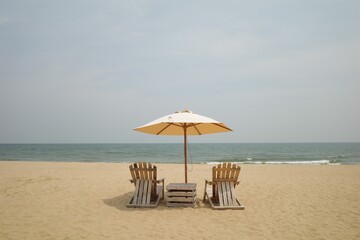 On middle frame Beach Wooden chairs and a parasol on sand beach