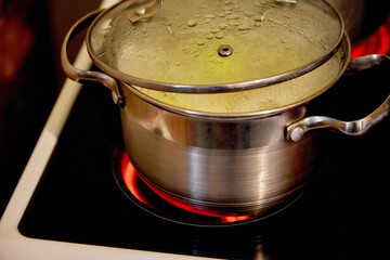 Boiling water in a saucepan on an electric stove in the kitchen. Lunch or dinner is cooked on the stove in a saucepan.