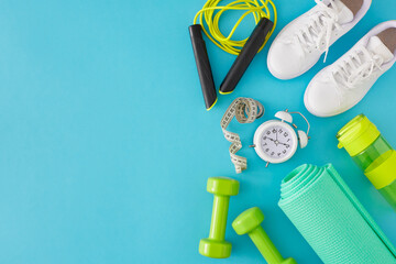 Creative sports concept. Flat lay photo of green dumbbells, exercise mat, skipping rope, white...