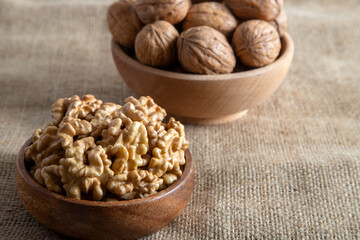 Peeled walnuts and whole walnuts on burlap sack 