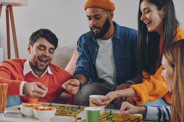 Happy young people playing board game while enjoying carefree time together