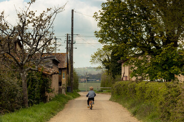 enfant sur un vélo dans une rue d'un village de campagne