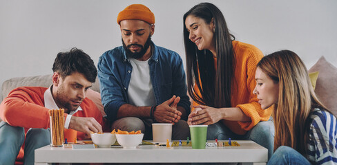 Beautiful young people playing board game while enjoying carefree time together