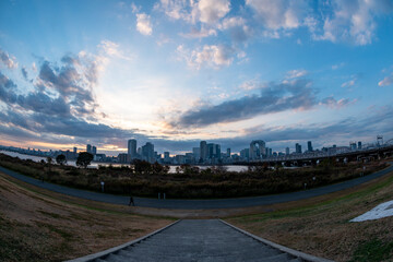 View of a park with buildings, a river and a bridge in the background during sunrise