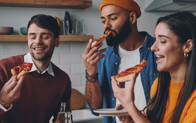 Happy young people eating pizza while enjoying fun time together