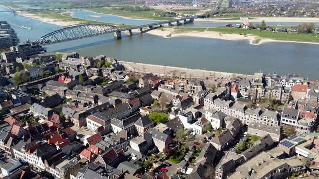 Aerial view panning over Nijmegen showing Waal river barge moving past and the two bridges connecting the city centre Stevenskerk in background beautiful town located in Gelderland province 4k