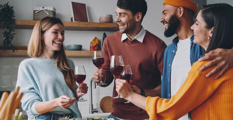 Group of beautiful young people talking and smiling while enjoying dinner at home together