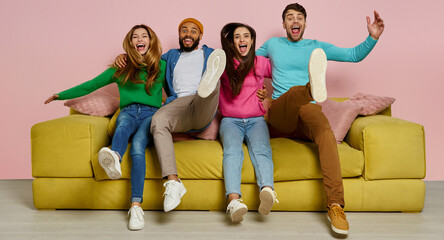 Studio shot of happy young people embracing and jumping on the couch together