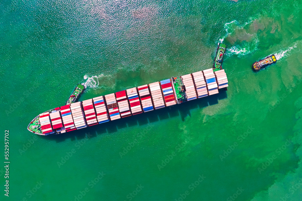 Wall mural container ship sailing in green sea and tugboat drag shipping to seaport.