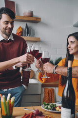 Beautiful young people toasting with wine while spending time at home together